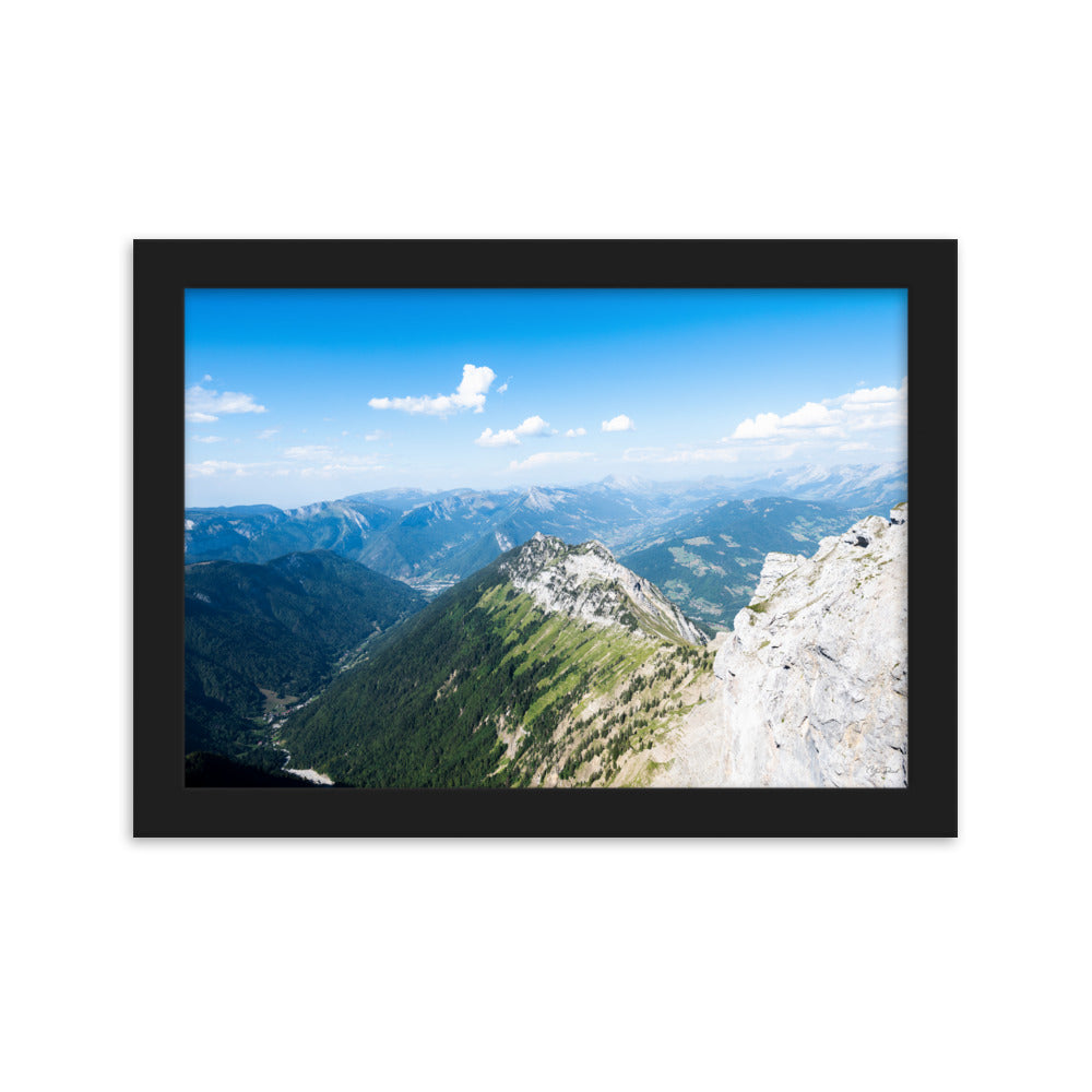 Photographie panoramique des Alpes avec montagnes robustes, vallées verdoyantes, nuages flottants et ciel bleu azur.