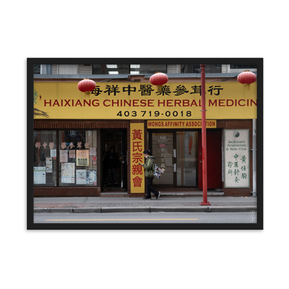 Photographie de rue à Calgary montrant une femme avec un masque abaissé devant une boutique d'herbes médicinales chinoises, capturée par Galdric Sibiude, reflétant le quotidien urbain.