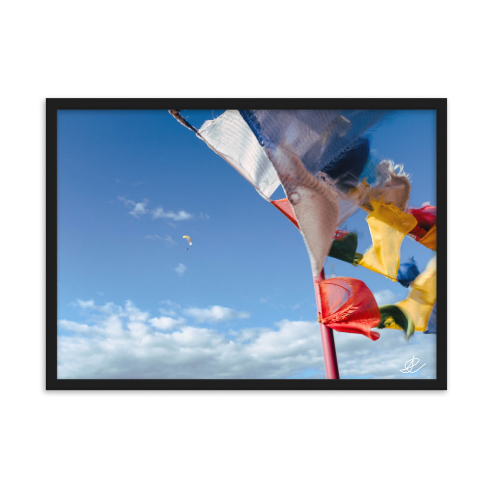 Photographie capturant des drapeaux colorés ondulant au vent et un parapente dans un ciel bleu, par Ilan Shoham, symbolisant la joie et l'esprit d'aventure.