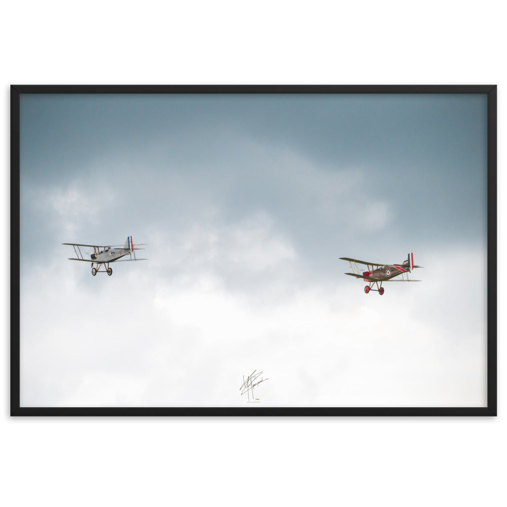 Deux avions de combat de la Première Guerre Mondiale s'élevant contre un ciel gris-blanc, encapsulant l'héroïsme de l'époque. Poster encadré de haute qualité signé 'Tagazou'.