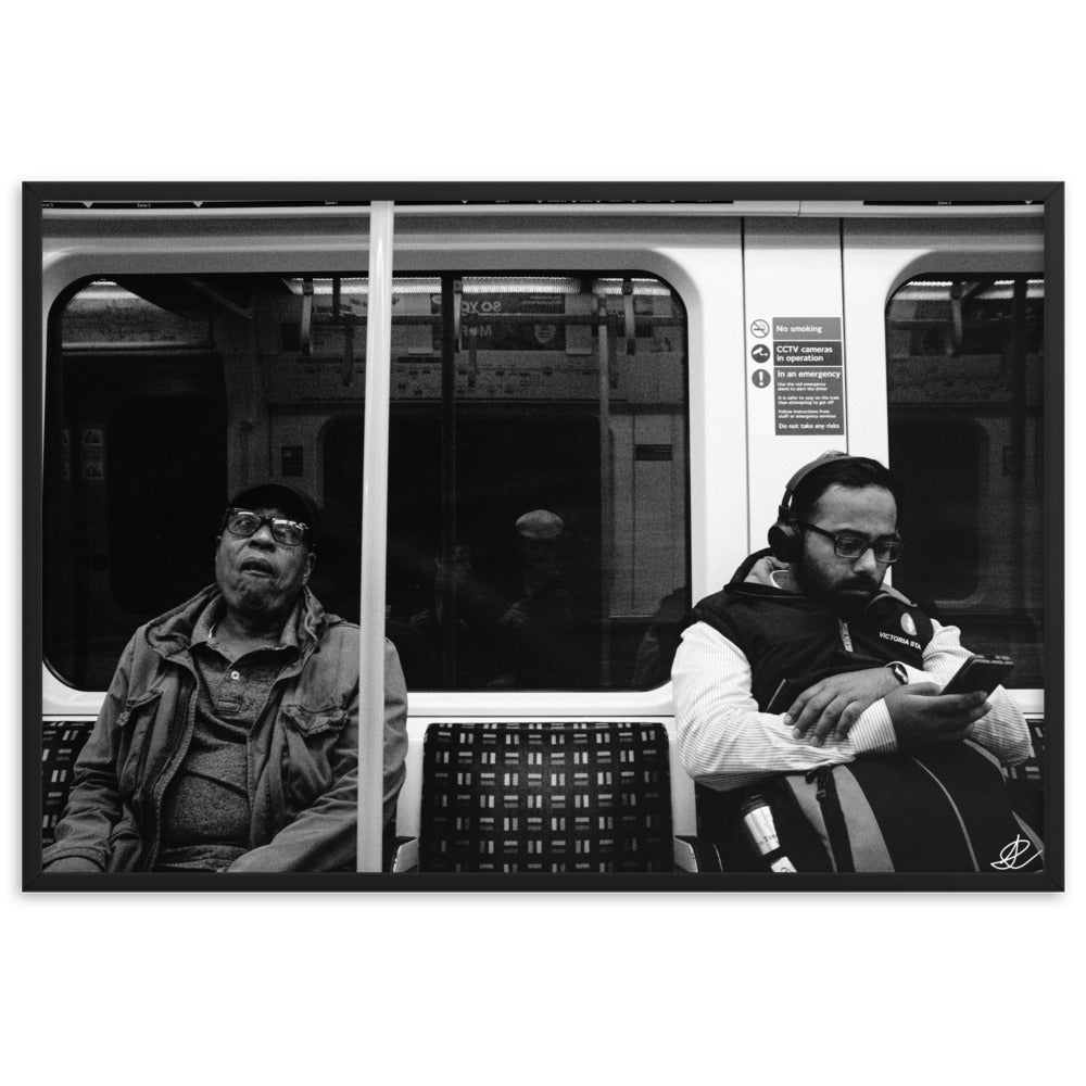 Poster encadré 'Fin de journée' en noir et blanc par Ilan Shoham, capturant une scène paisible du métro londonien avec un siège vide encadré par deux individus assis, symbolisant les distances sociales dans l'agitation urbaine.