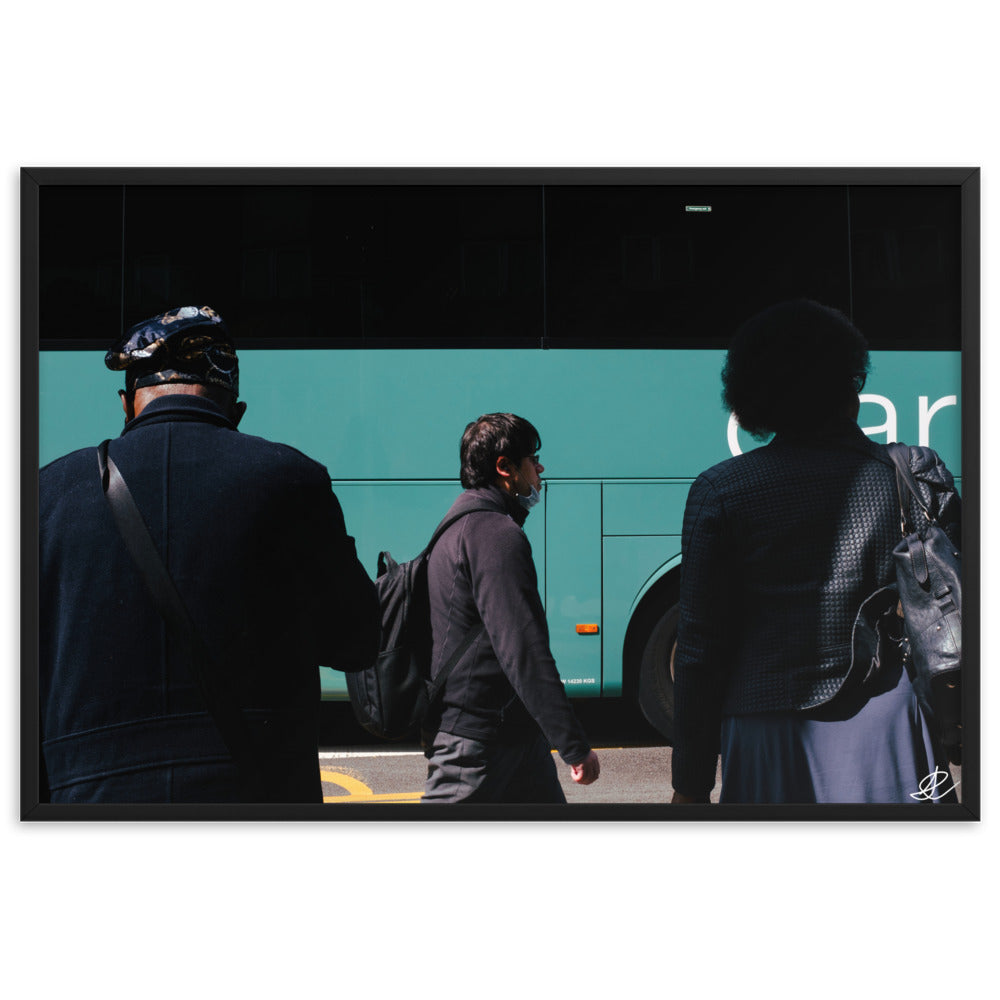 Photographie encadrée 'Arrêt de Bus' par Ilan Shoham, illustrant une scène urbaine londonienne riche en narratif, avec deux individus au premier plan, un passant solitaire au second, et un bus flou en arrière-plan, symbolisant la complexité et la beauté du quotidien.