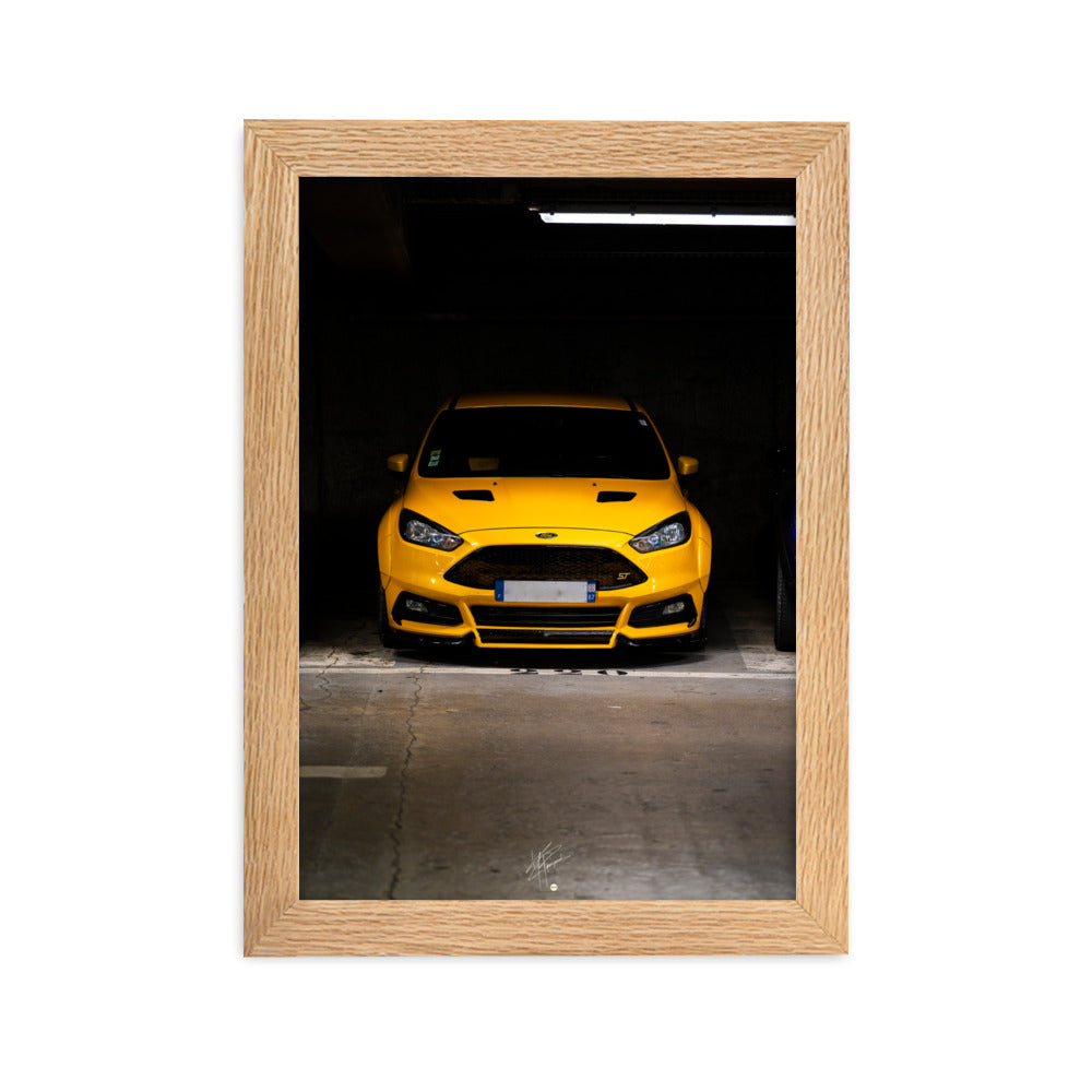 Vue frontale d'une Ford Focus ST en éclatant jaune, mise en lumière dans un parking souterrain avec un éclairage distinctif, encadrement en chêne.