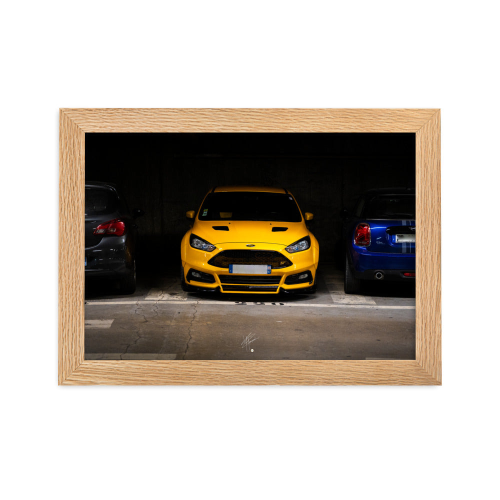 Ford Focus ST jaune brillamment éclairée dans un parking souterrain sombre, encadrement en bois de chêne massif.