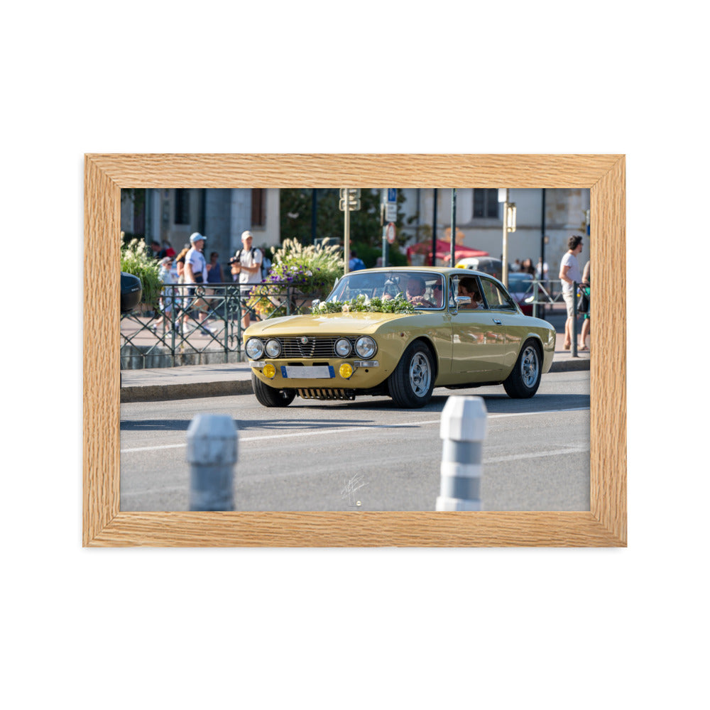 Photographie en angle de la voiture Alpha Romeo GTV, mise en valeur par sa teinte jaune vibrante et sa forme emblématique, stationnée élégamment dans une rue de ville.