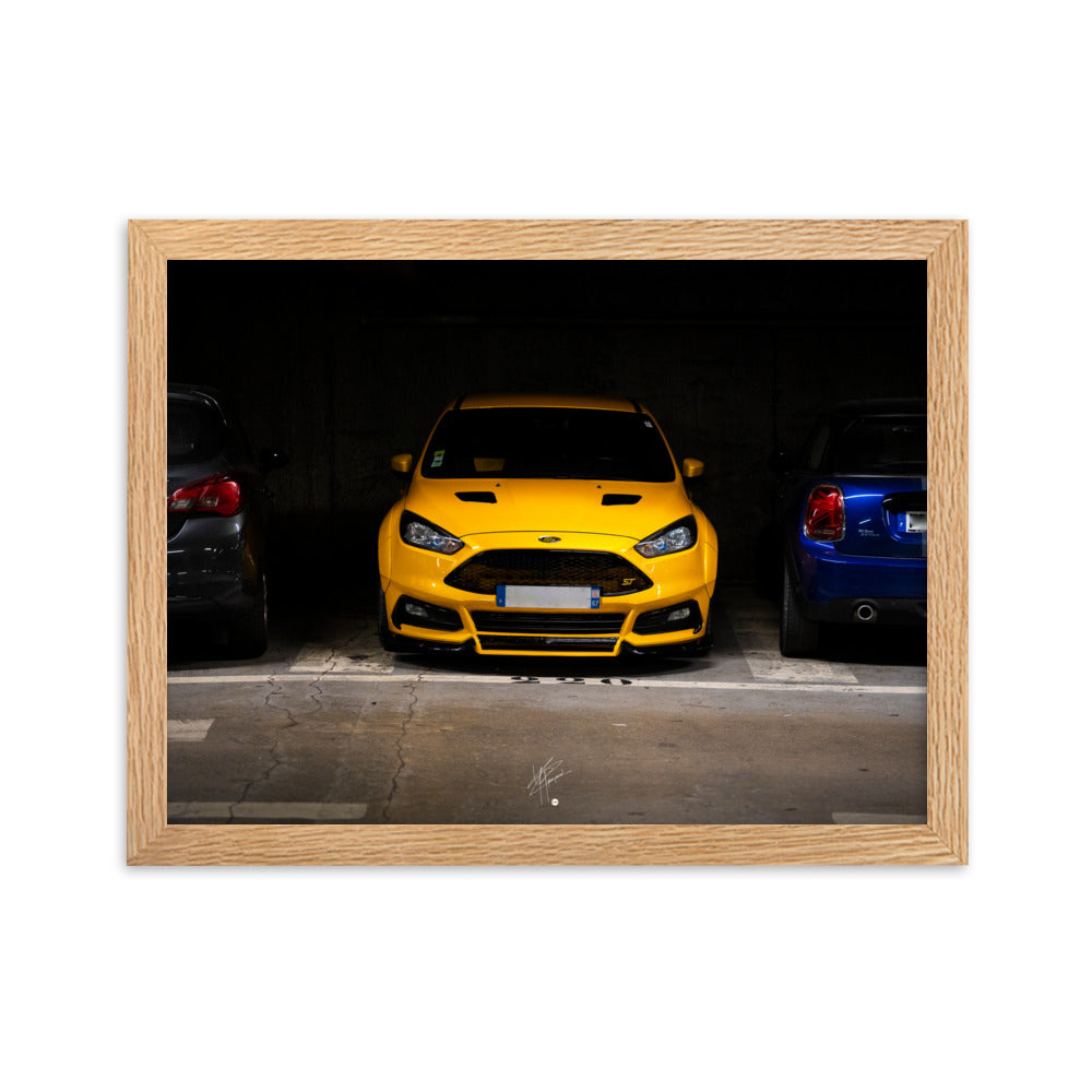 Ford Focus ST jaune brillamment éclairée dans un parking souterrain sombre, encadrement en bois de chêne massif.