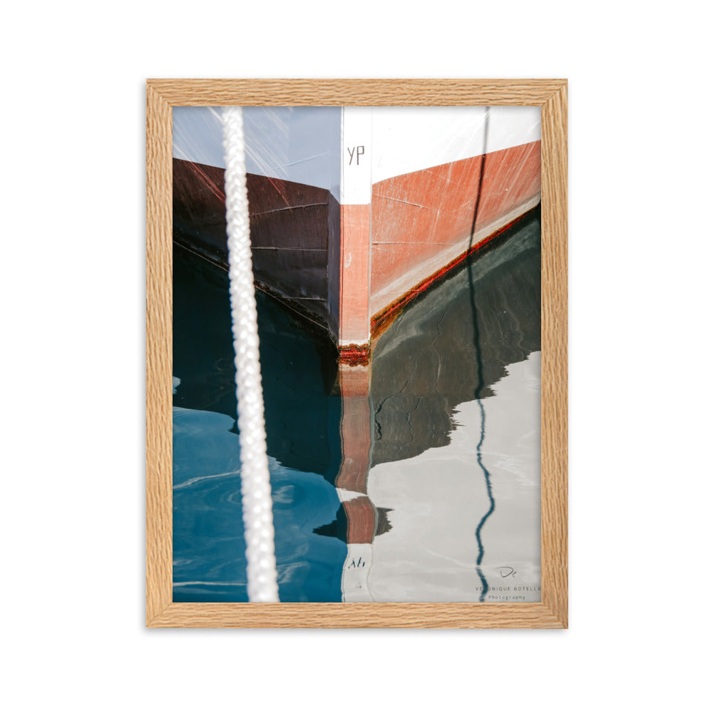 Poster encadré 'Dolce vita' montrant un pittoresque bateau à coque en bois reflétant sur les eaux calmes du port, photographié par Veronique Botella.