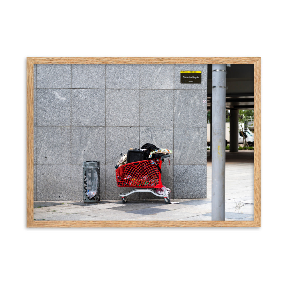 Photographie d'un caddie rouge abandonné à La Défense, juxtaposé à une poubelle, évoquant une méditation sur la consommation et l'abandon dans un contexte urbain moderne.