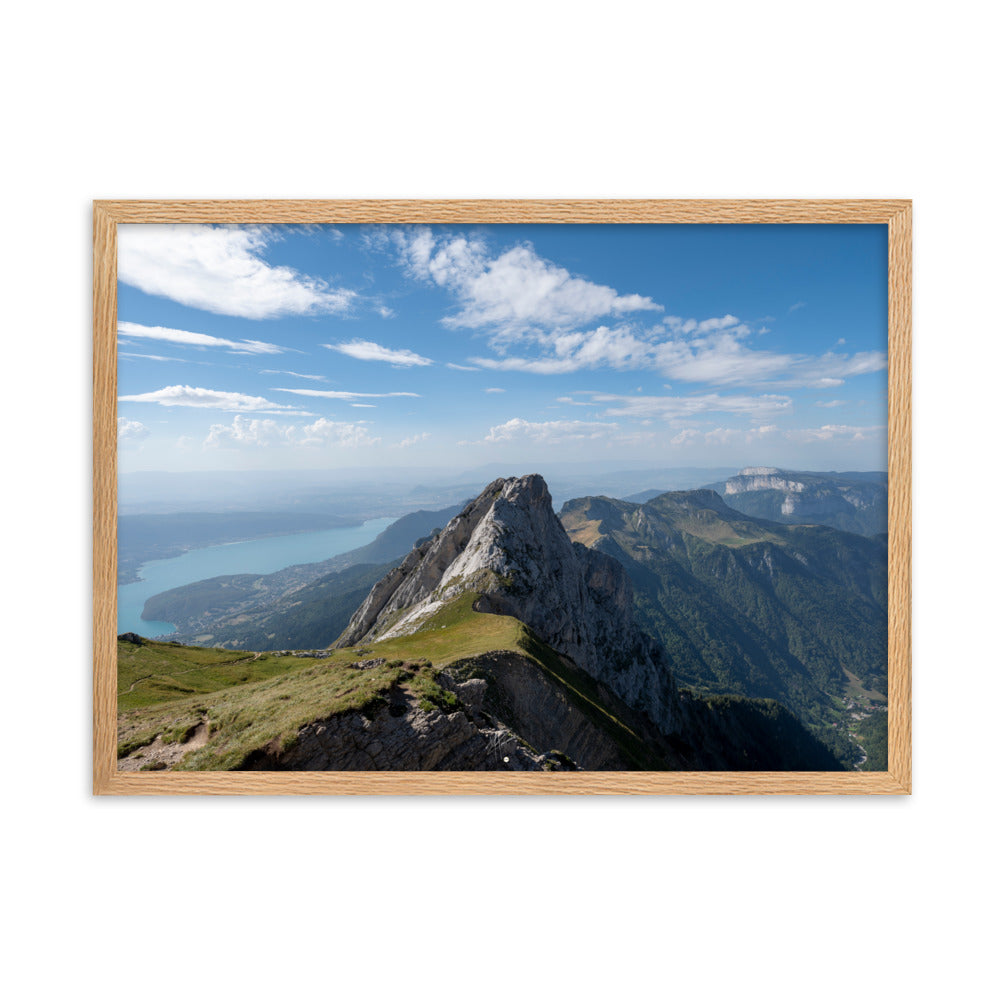 Vue aérienne du Col du Varo avec les montagnes rocheuses en avant-plan et le Lac d'Annecy en arrière-plan, encadré en chêne.