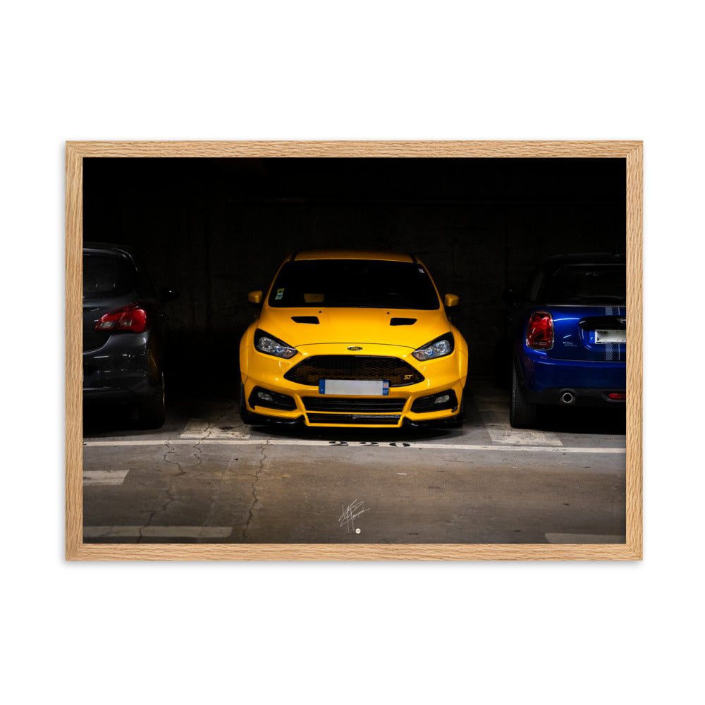 Ford Focus ST jaune brillamment éclairée dans un parking souterrain sombre, encadrement en bois de chêne massif.