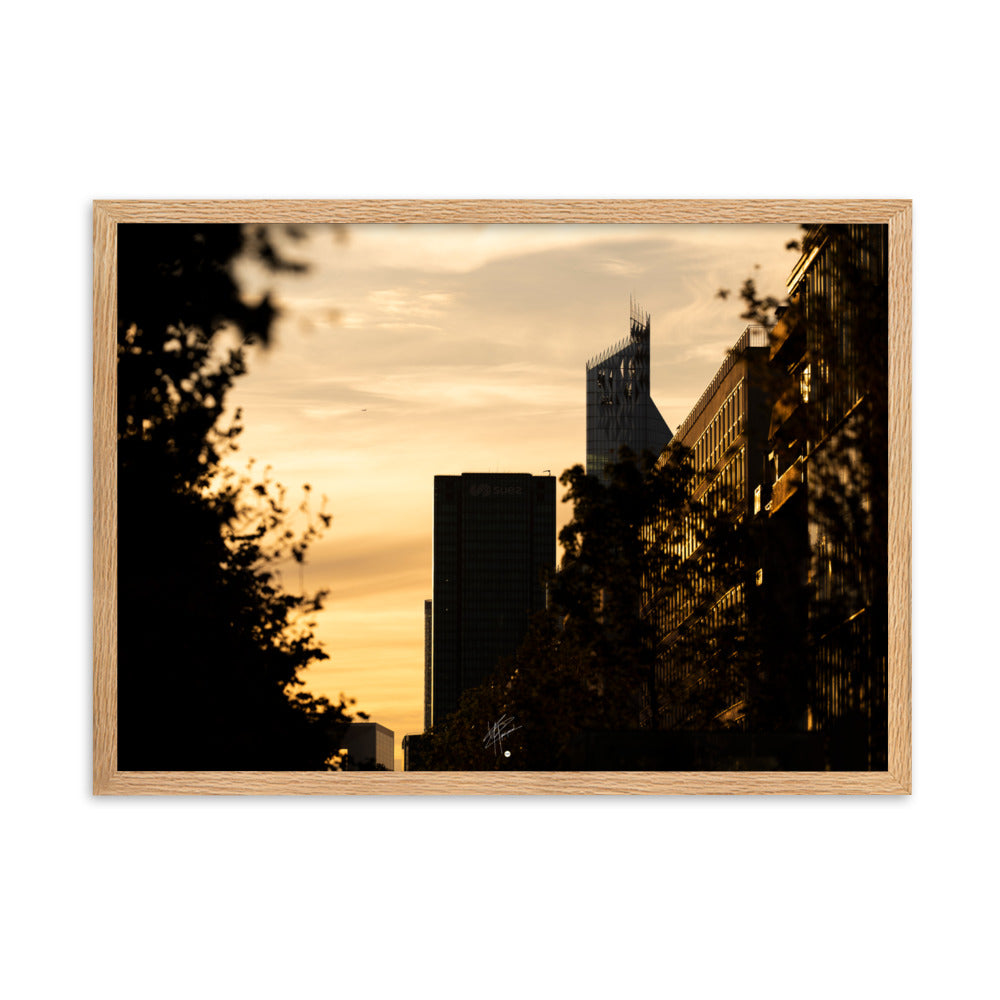 Vue panoramique d'un coucher de soleil à La Défense avec des tons oranges dominants, mettant en valeur l'Arche et le siège de SUEZ, complétés par la silhouette d'un avion à l'horizon.