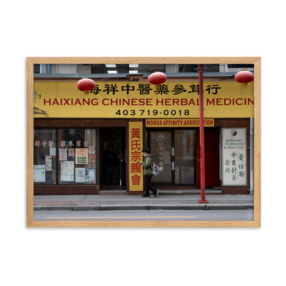 Photographie de rue à Calgary montrant une femme avec un masque abaissé devant une boutique d'herbes médicinales chinoises, capturée par Galdric Sibiude, reflétant le quotidien urbain.