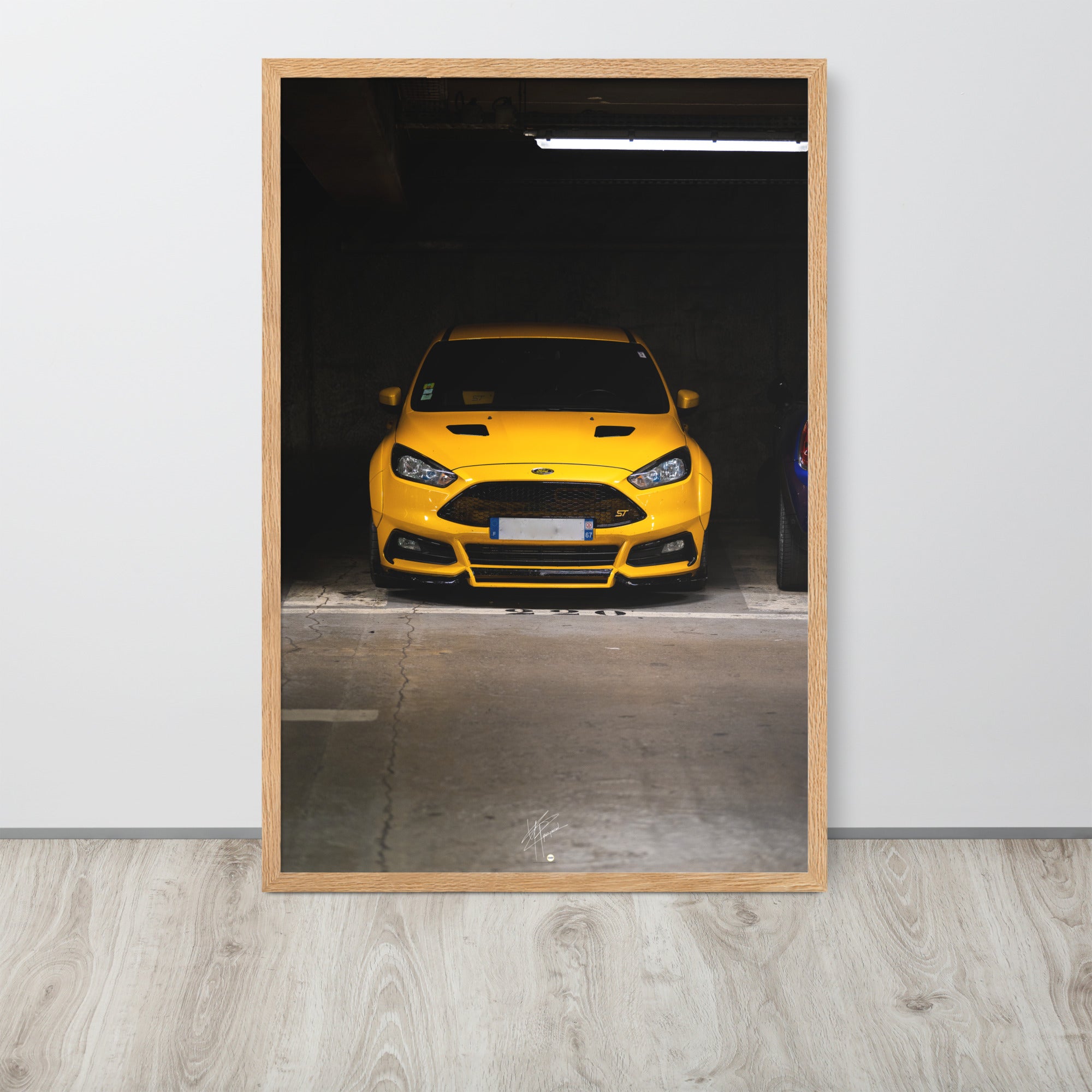 Vue frontale d'une Ford Focus ST en éclatant jaune, mise en lumière dans un parking souterrain avec un éclairage distinctif, encadrement en chêne.