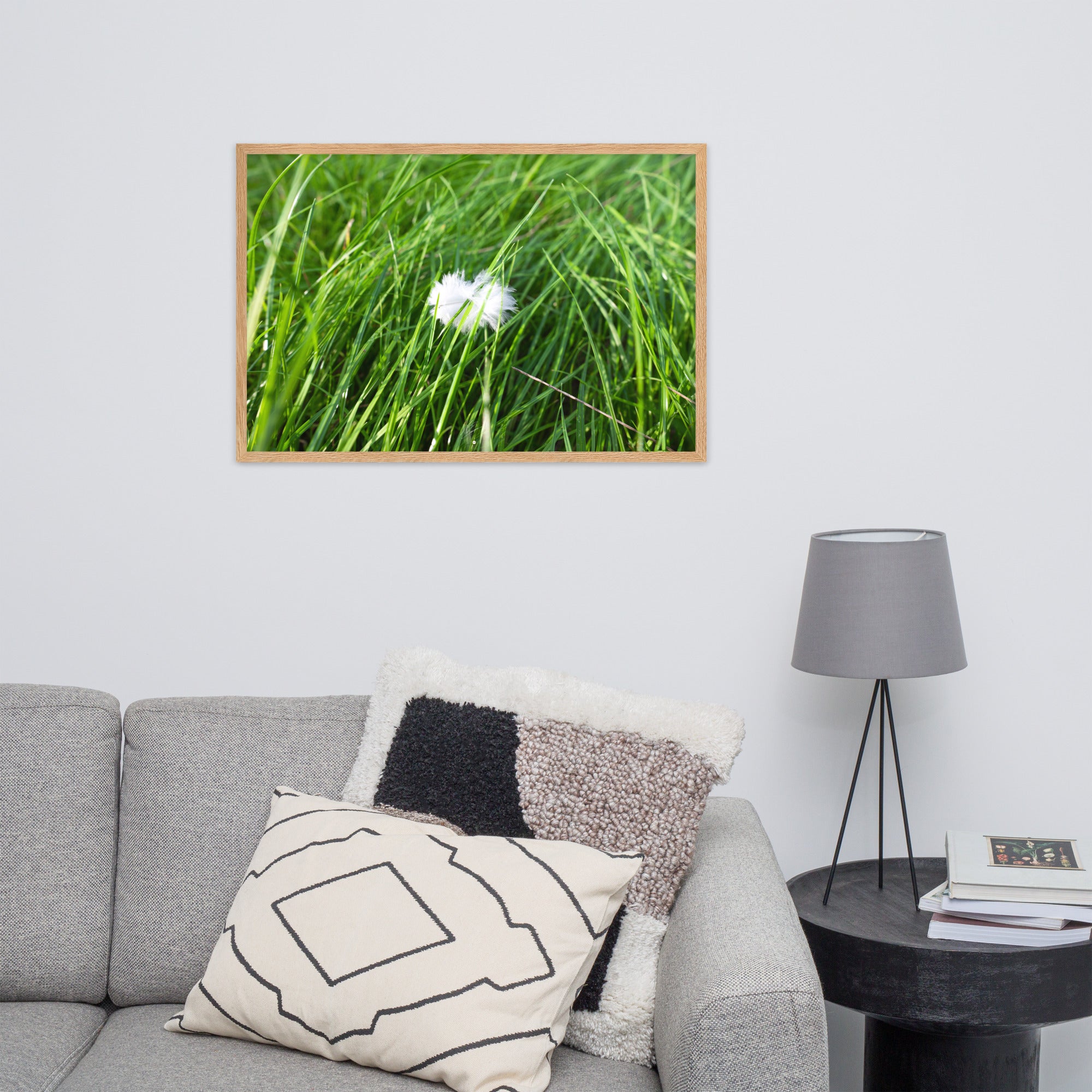 Photographie d'une plume blanche solitaire reposant paisiblement sur une herbe verte, encapsulant une ambiance de calme et de sérénité.
