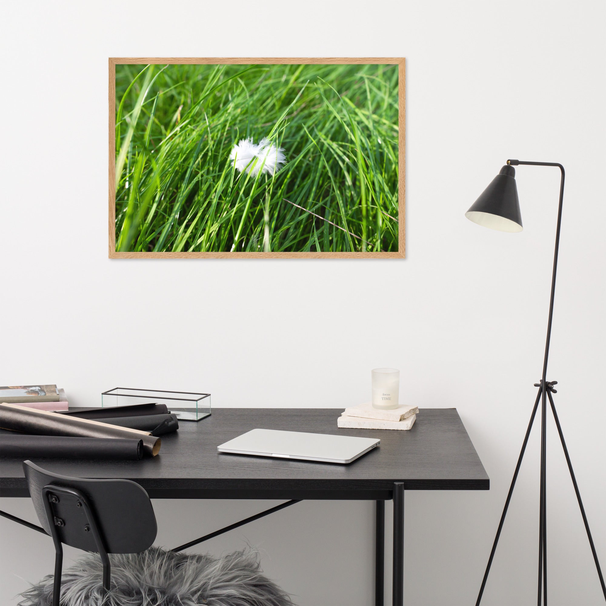 Photographie d'une plume blanche solitaire reposant paisiblement sur une herbe verte, encapsulant une ambiance de calme et de sérénité.