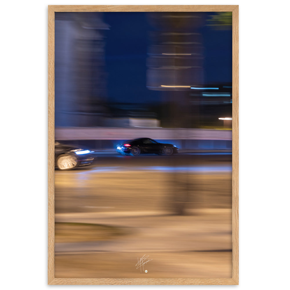 Photographie de la Place de l'Étoile capturant une Porsche au milieu de lumières floues de la circulation. La technique de pause longue crée un contraste saisissant entre mouvement et immobilité, illustrant l'effervescence parisienne.
