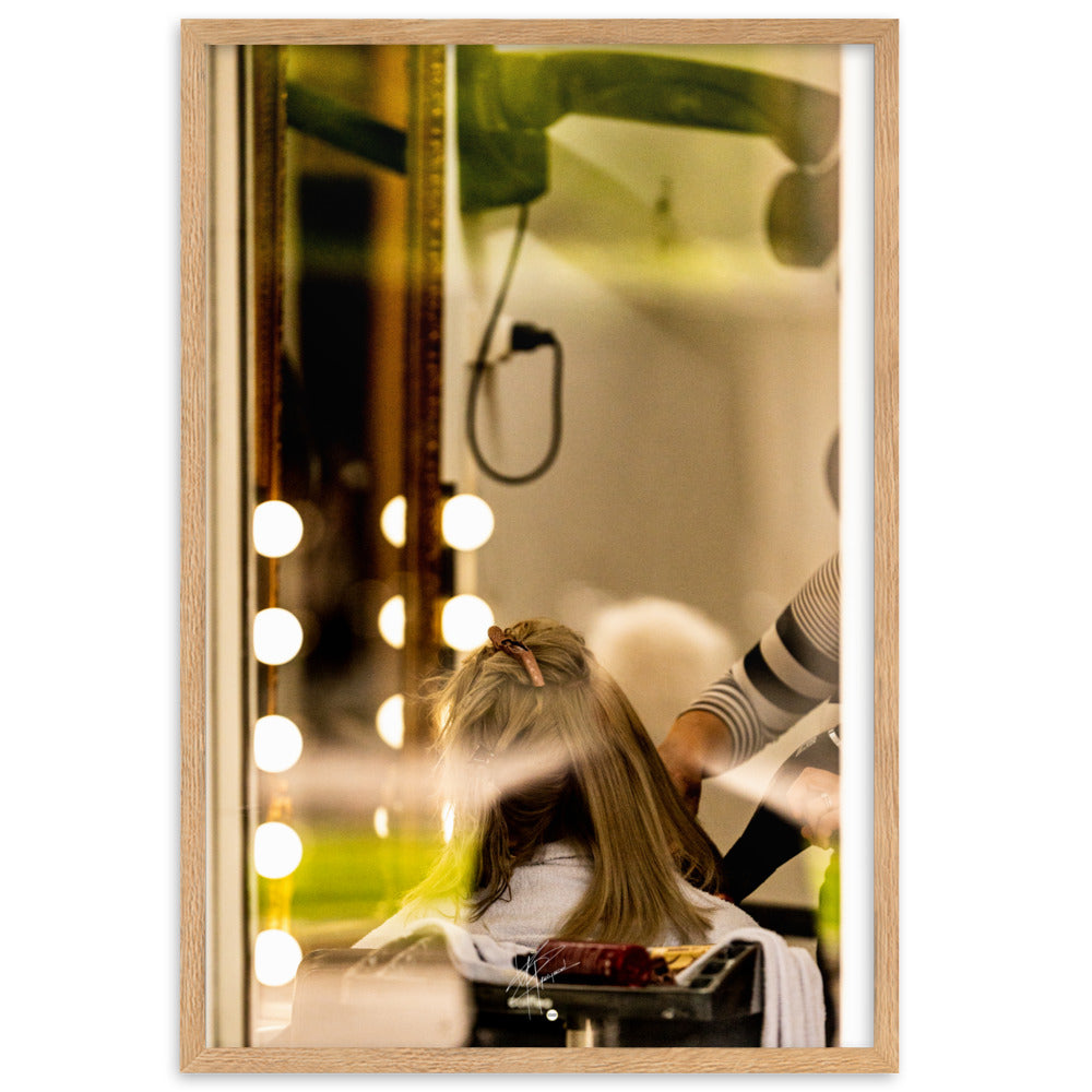 Photographie d'une scène à travers la vitre d'un salon de coiffure, révélant un moment ordinaire mais expressif d'une coiffeuse en plein travail.