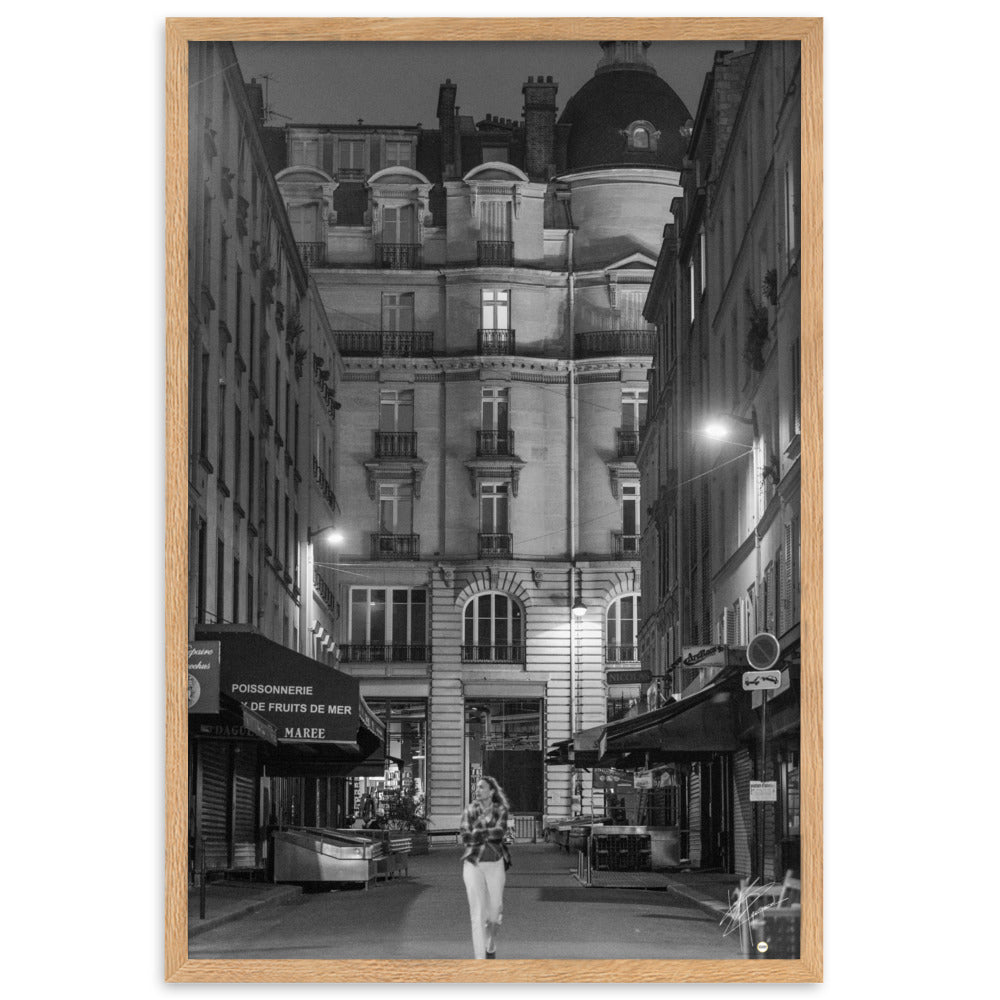 Photographie en noir et blanc d'une rue parisienne déserte la nuit, illuminée par les lumières douces des lampadaires, évoquant une atmosphère mystérieuse et mélancolique.