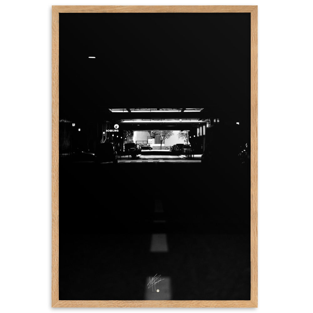 Photographie nocturne en noir et blanc d'une rue urbaine, avec une enseigne 'BOWLING' éclairée, contrastant avec la profonde obscurité environnante.
