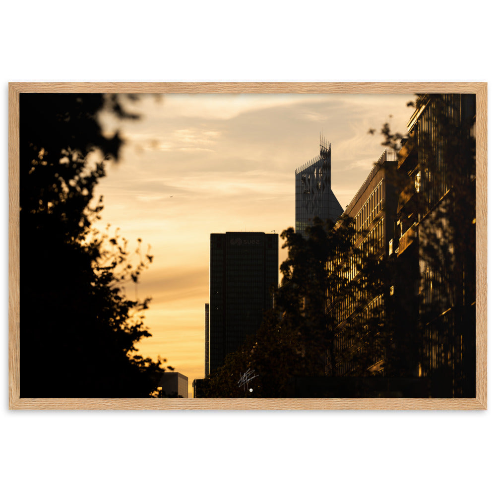 Vue panoramique d'un coucher de soleil à La Défense avec des tons oranges dominants, mettant en valeur l'Arche et le siège de SUEZ, complétés par la silhouette d'un avion à l'horizon.