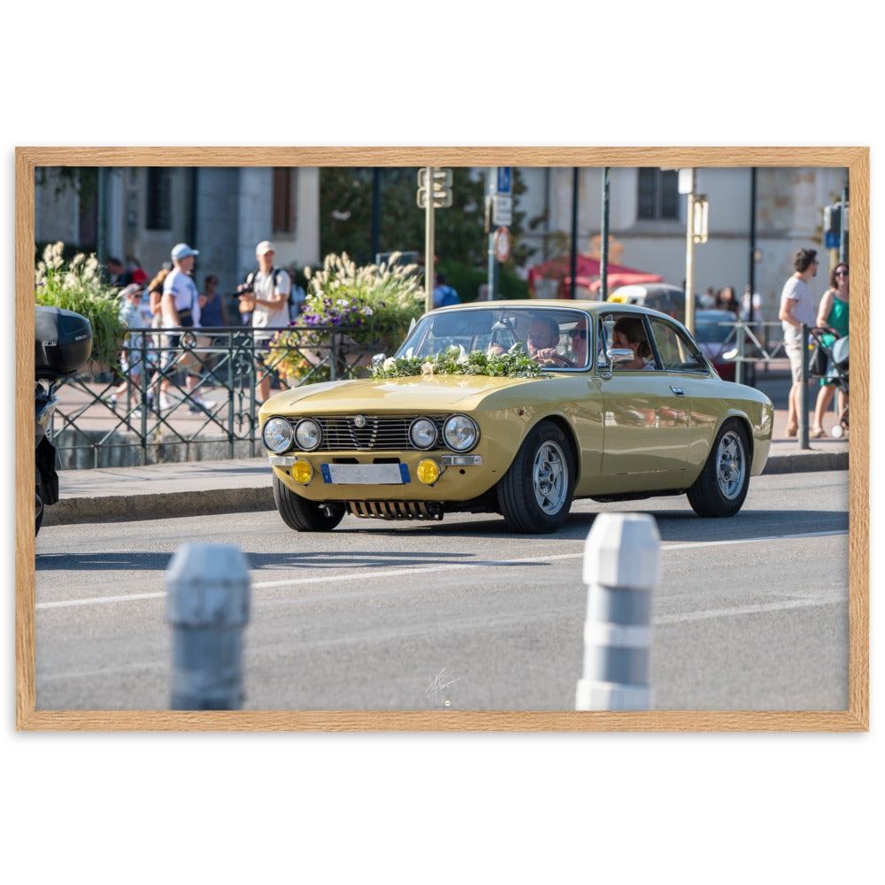 Photographie en angle de la voiture Alpha Romeo GTV, mise en valeur par sa teinte jaune vibrante et sa forme emblématique, stationnée élégamment dans une rue de ville.