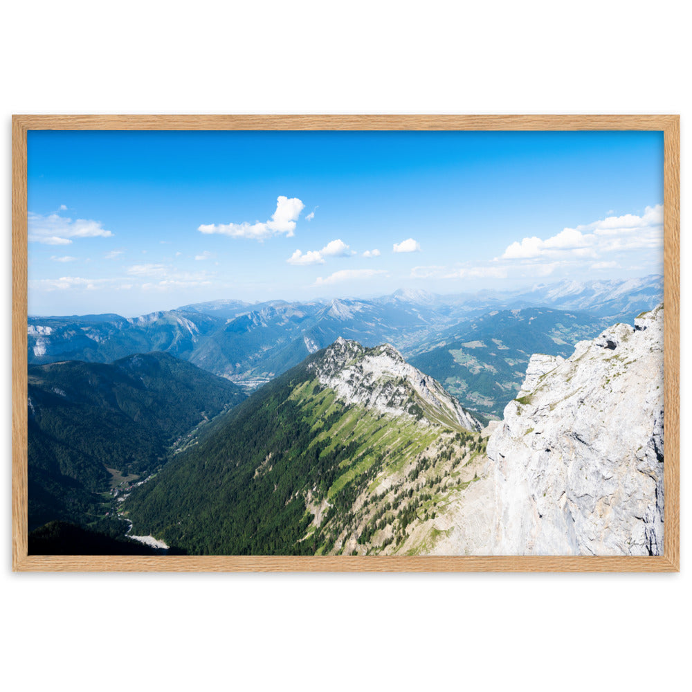 Photographie panoramique des Alpes avec montagnes robustes, vallées verdoyantes, nuages flottants et ciel bleu azur.