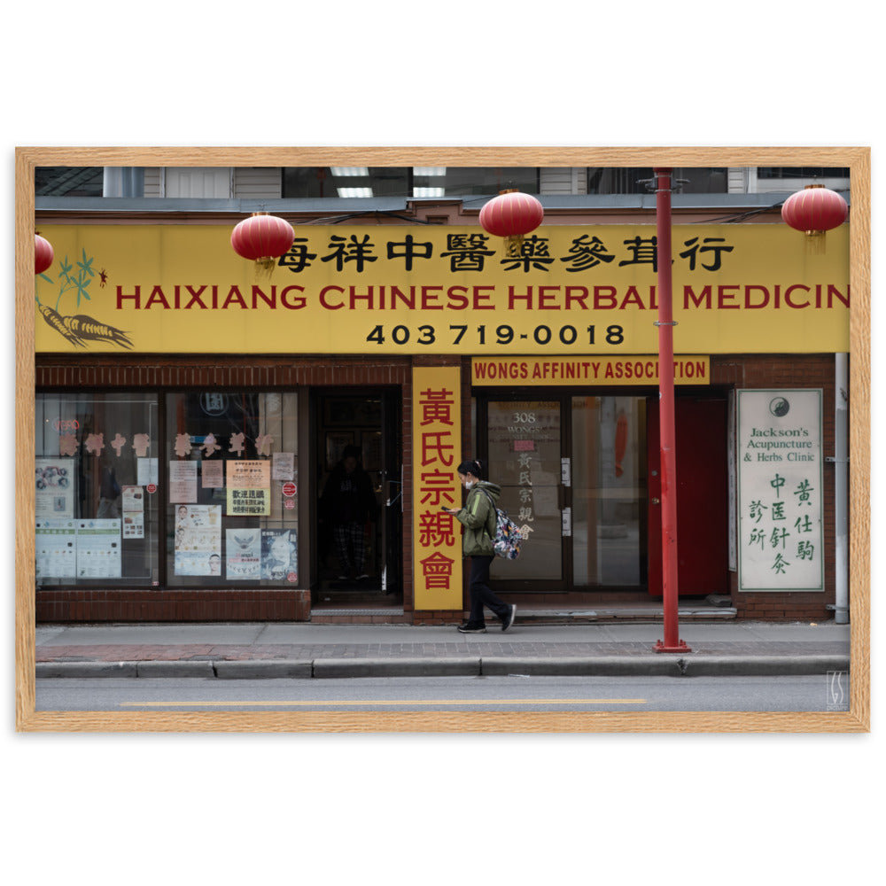 Photographie de rue à Calgary montrant une femme avec un masque abaissé devant une boutique d'herbes médicinales chinoises, capturée par Galdric Sibiude, reflétant le quotidien urbain.