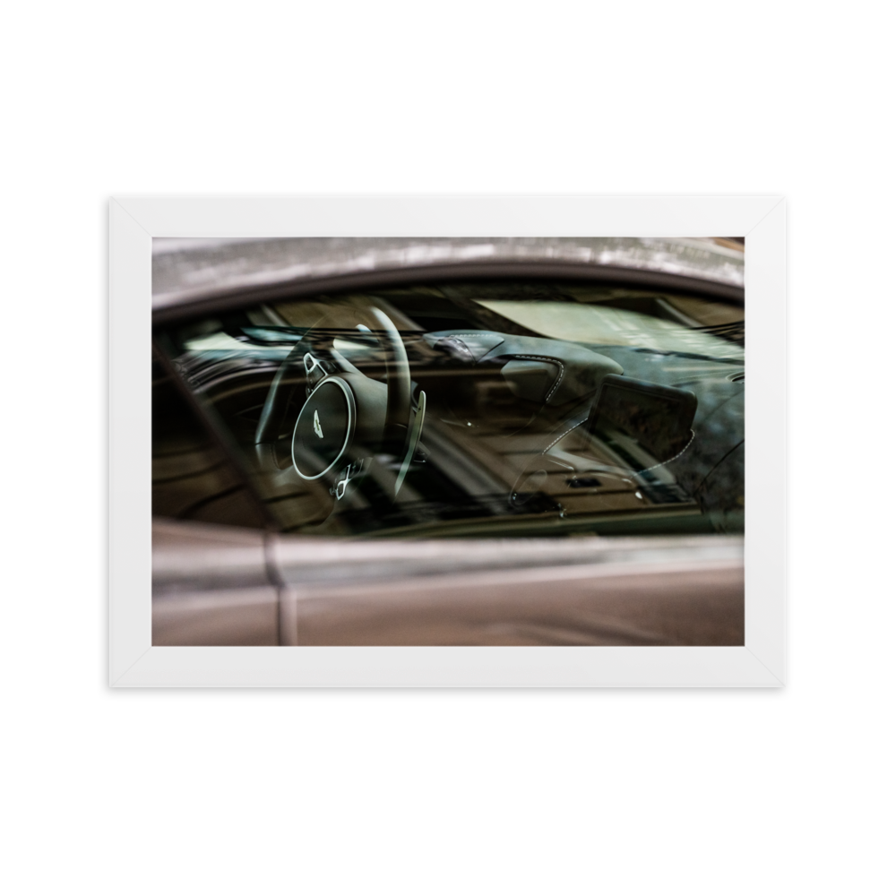 Photographie de l'intérieur d'une Aston Martin Vantage, mettant en valeur le tableau de bord en cuir et le volant.
