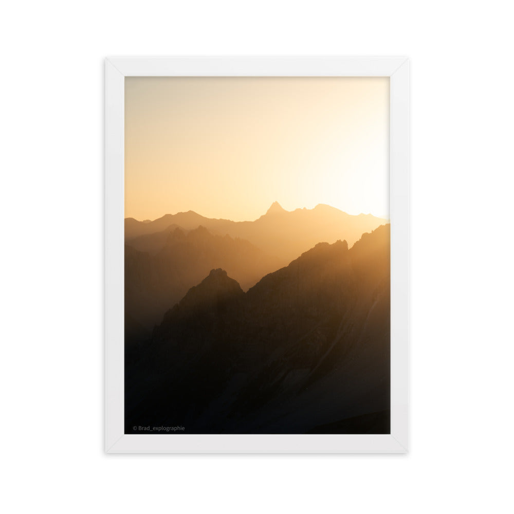 Lever du soleil illuminant des montagnes imposantes, photographié par Brad_explographie, présenté dans un cadre élégant.