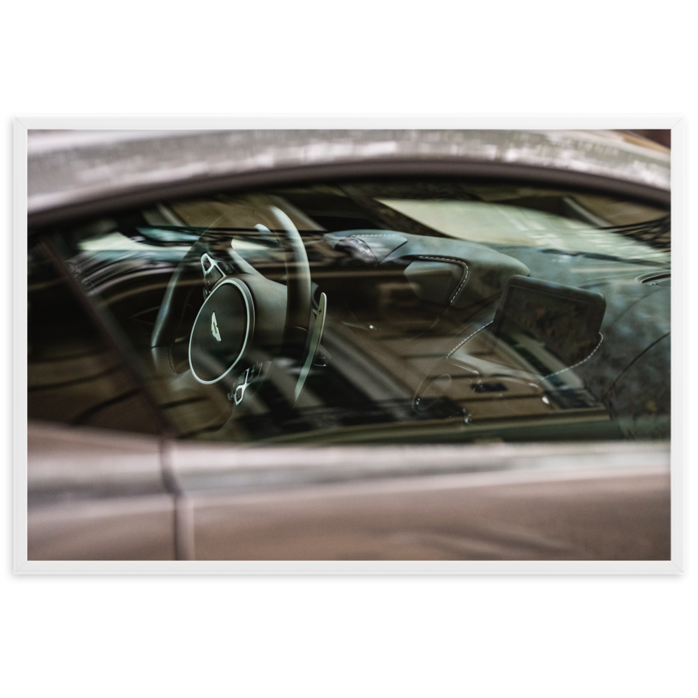 Photographie de l'intérieur d'une Aston Martin Vantage, mettant en valeur le tableau de bord en cuir et le volant.