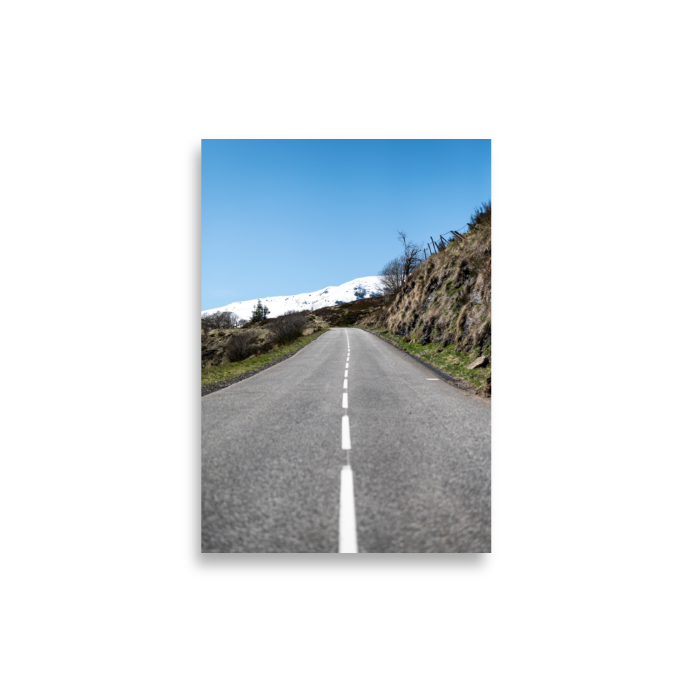 Photographie de route rurale menant à une montagne enneigée sous un ciel bleu dans le Cantal - Poster de paysage du Cantal