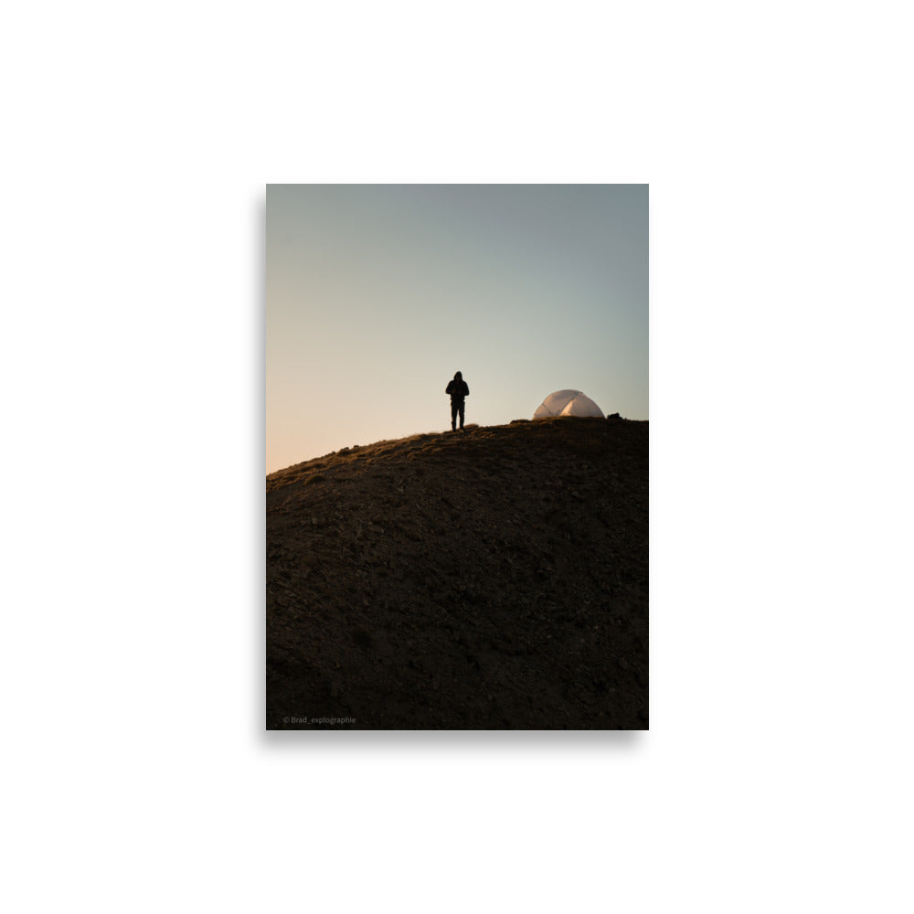 Randonneur face à l'aube, à côté de sa tente, sur une colline, capturé par Brad_explographie.
