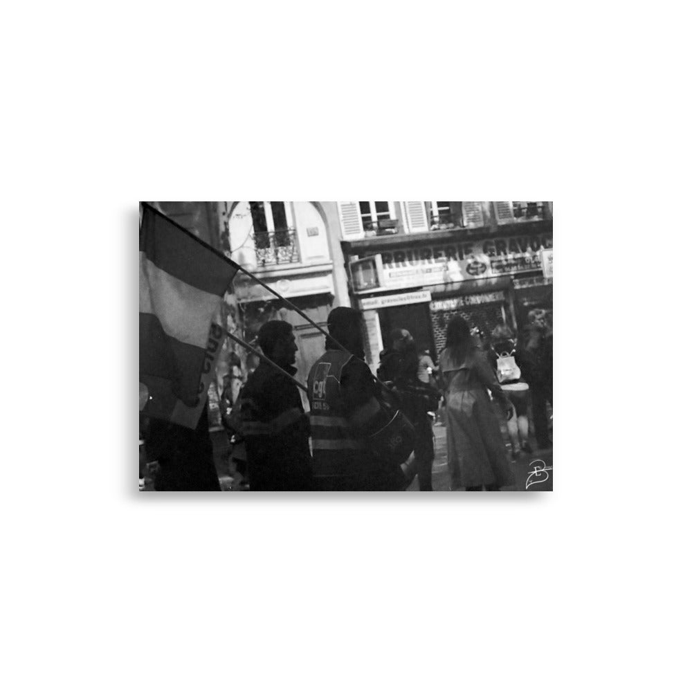 Photographie en noir et blanc d'une scène du 1er mai à Paris, montrant deux militants de la CGT marchant avec fierté, drapeau à la main, capturée par Eli Bernet en technique argentique.