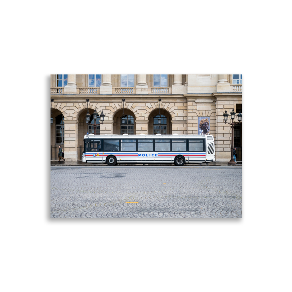 Photographie d'un bus de la police stationné sur une rue pavée à Paris, avec un bâtiment historique en arrière-plan.