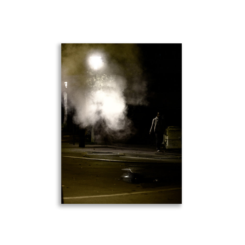 Photographie nocturne de Paris près du Rooftop Café Oz, montrant un homme passant à côté d'une fumée sortant d'une plaque sur le trottoir.