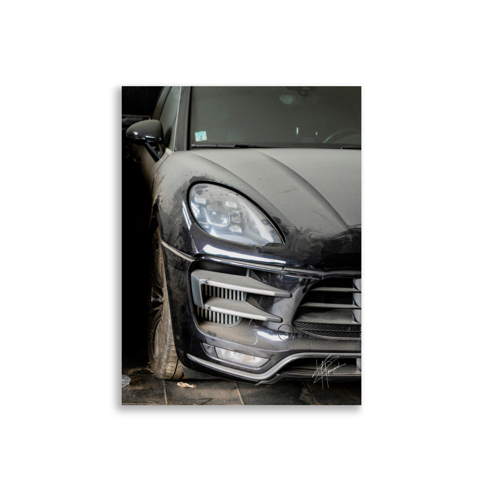 Photographie d'un Porsche Cayenne noir abandonné dans un garage poussiéreux.