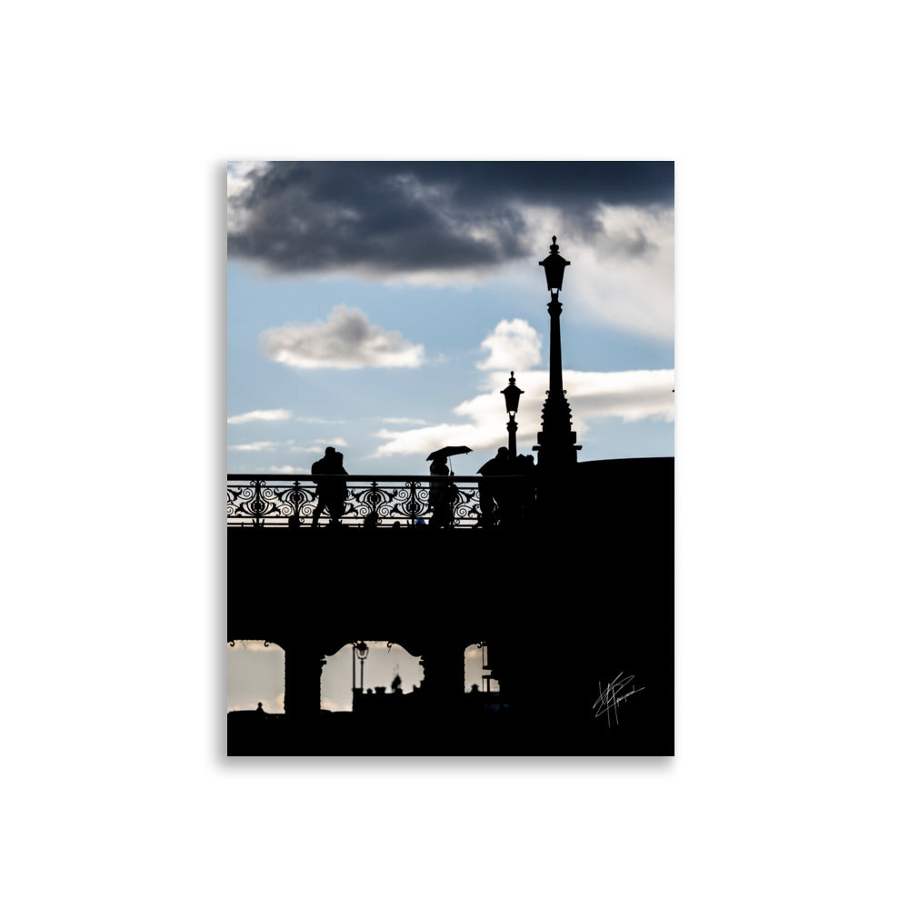 Des passants sur un pont parisien avec un ciel azur en arrière-plan, orné de nuages blancs et gris.