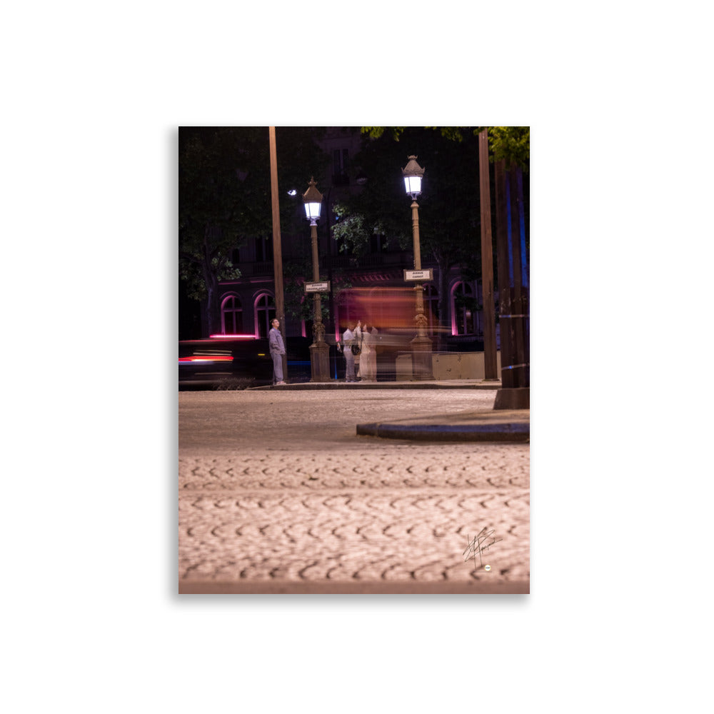 Photographie nocturne de l'Avenue de la Grande Armée à Paris, montrant quatre touristes prenant une photo, avec un arrière-plan de voitures en mouvement grâce à une longue exposition.