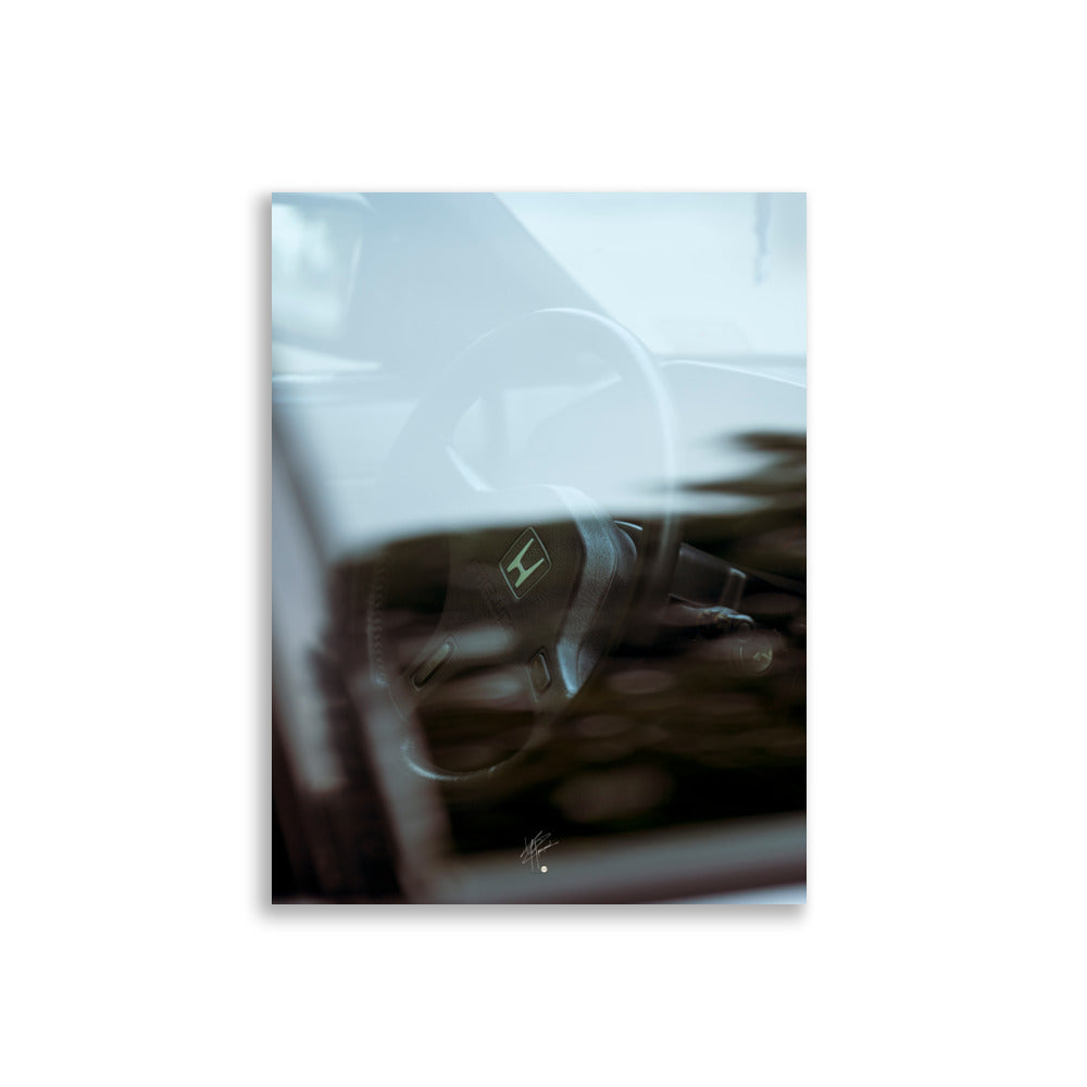 Volant d'une Honda vintage vu à travers la vitre de la voiture, embelli par des reflets lumineux.
