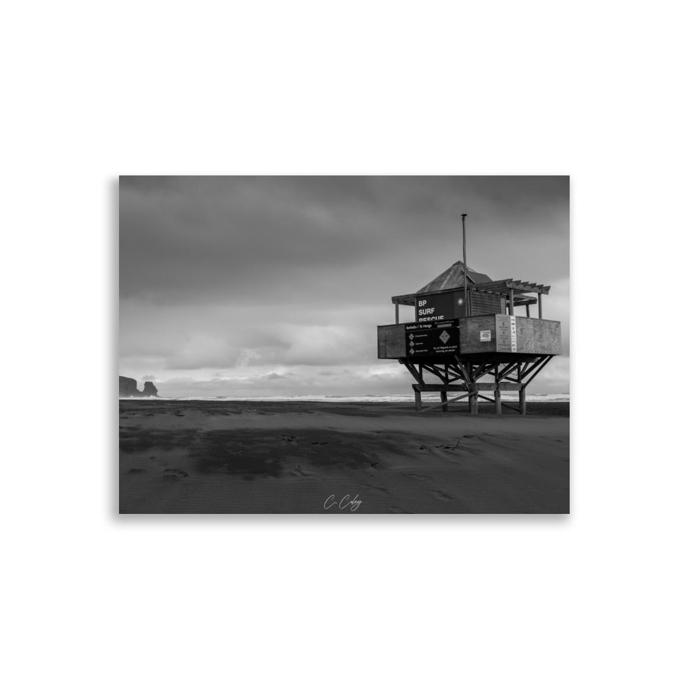 Photographie monochrome de l'emblématique abri sur pilotis des sauveteurs, dominant une plage néo-zélandaise, capturée par Charles Coley.