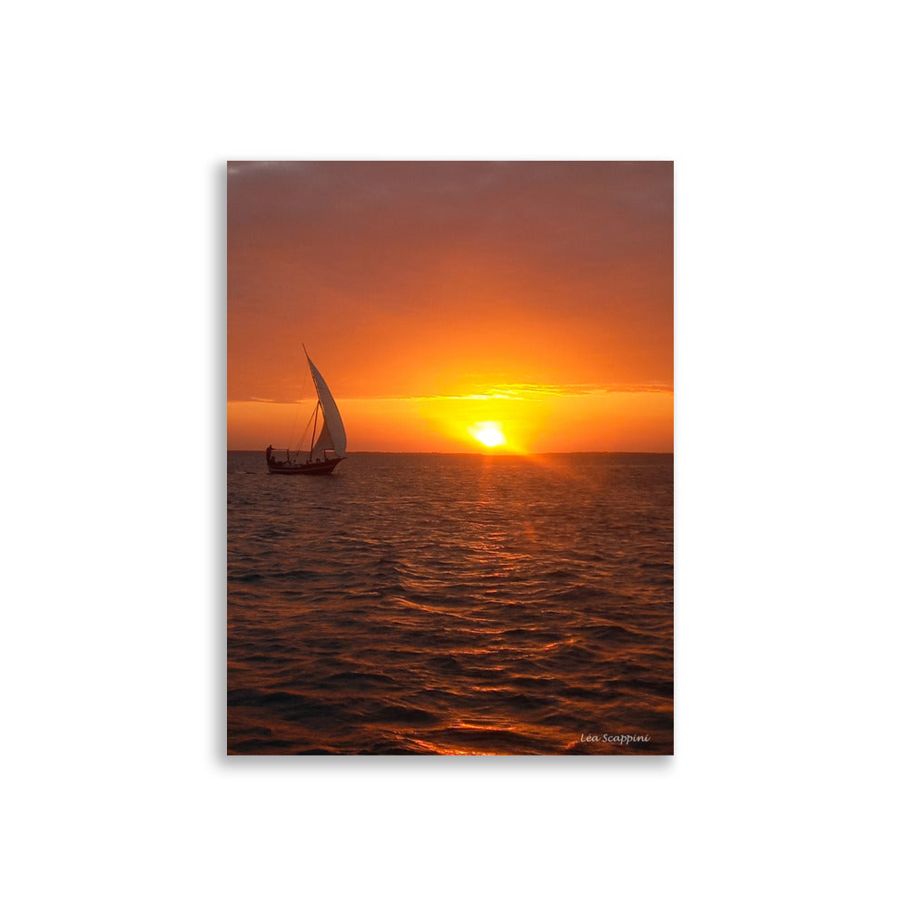 Photographie d'un dhow traditionnel naviguant sur l'océan au coucher du soleil, capturée par Léa Scappini, dépeignant une scène de tranquillité et de solitude apaisante.
