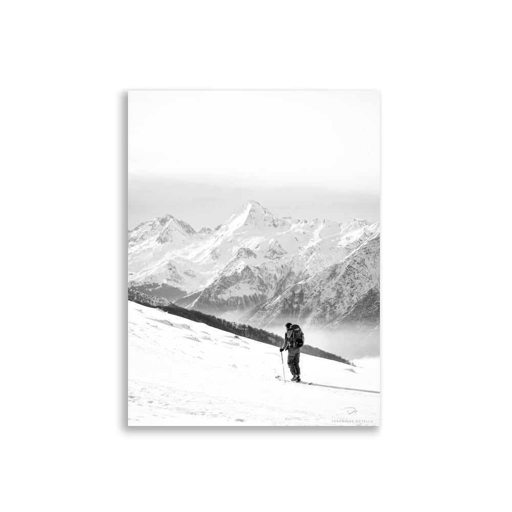 Photographie en noir et blanc d'un randonneur face aux montagnes enneigées, par Véronique Botella, illustrant la majesté et la solitude de la nature.