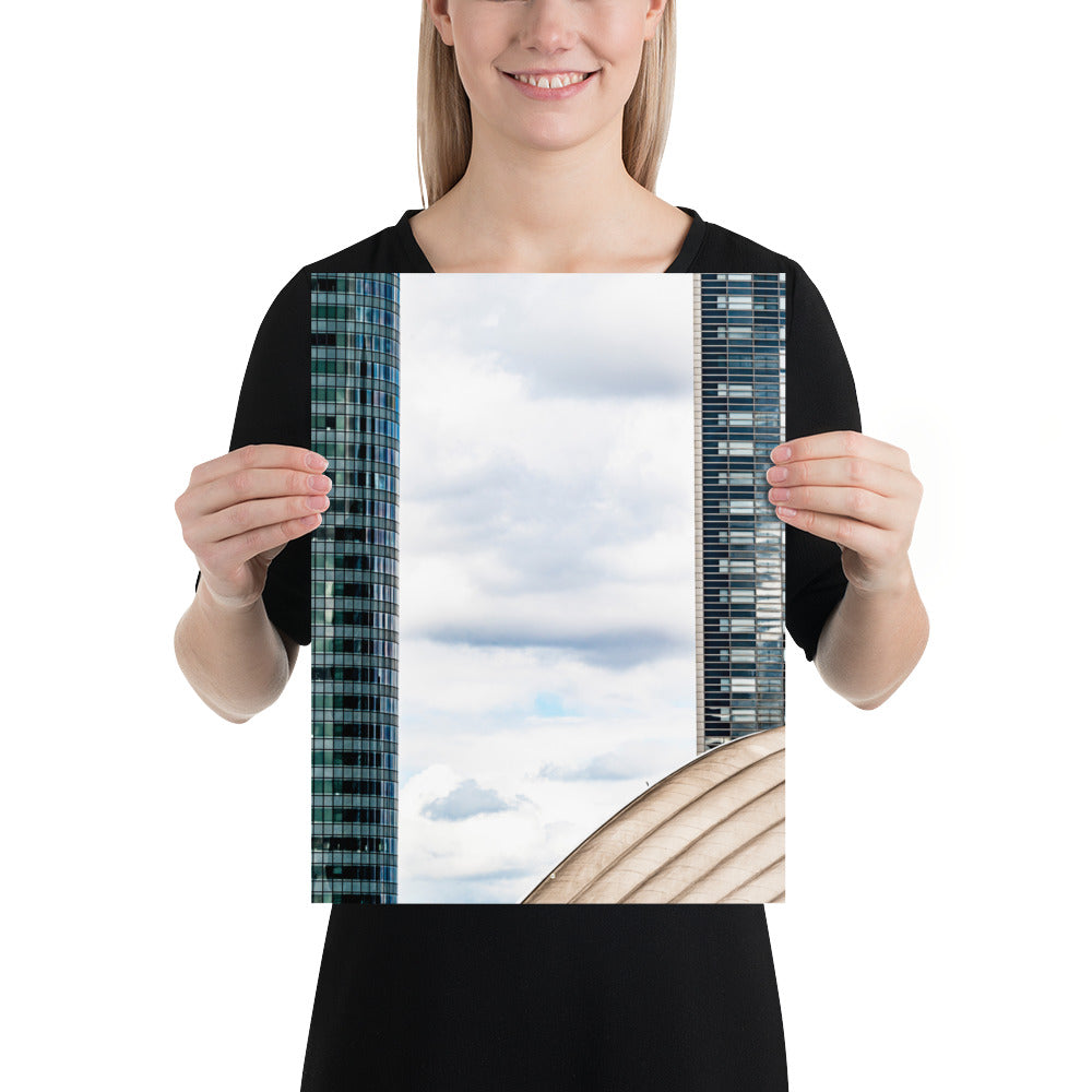 Fenêtre entre deux bâtiments en verre offrant une vue sur un ciel nuageux.