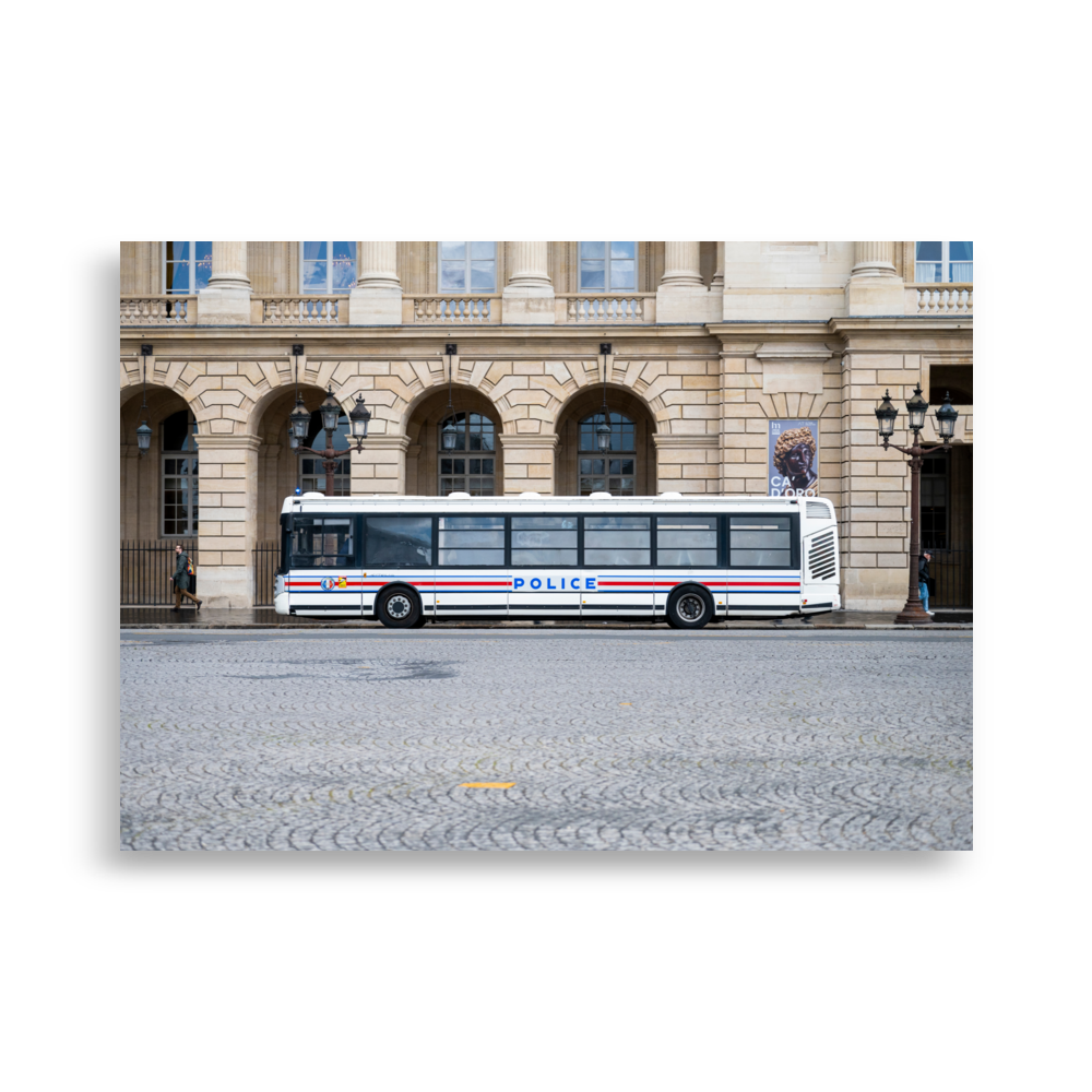 Photographie d'un bus de la police stationné sur une rue pavée à Paris, avec un bâtiment historique en arrière-plan.