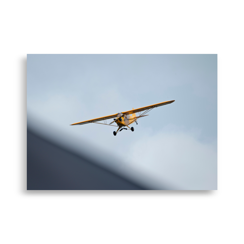 Photographie d'un Piper Cub jaune en plein vol.