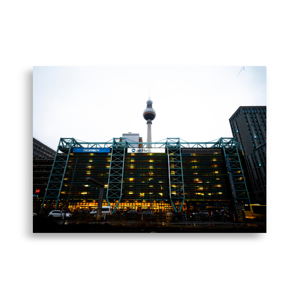 Photographie du parking moderne multi-étages "Parkhaus Rathauspassagen" à Berlin, illuminé avec la tour de télévision en arrière-plan.