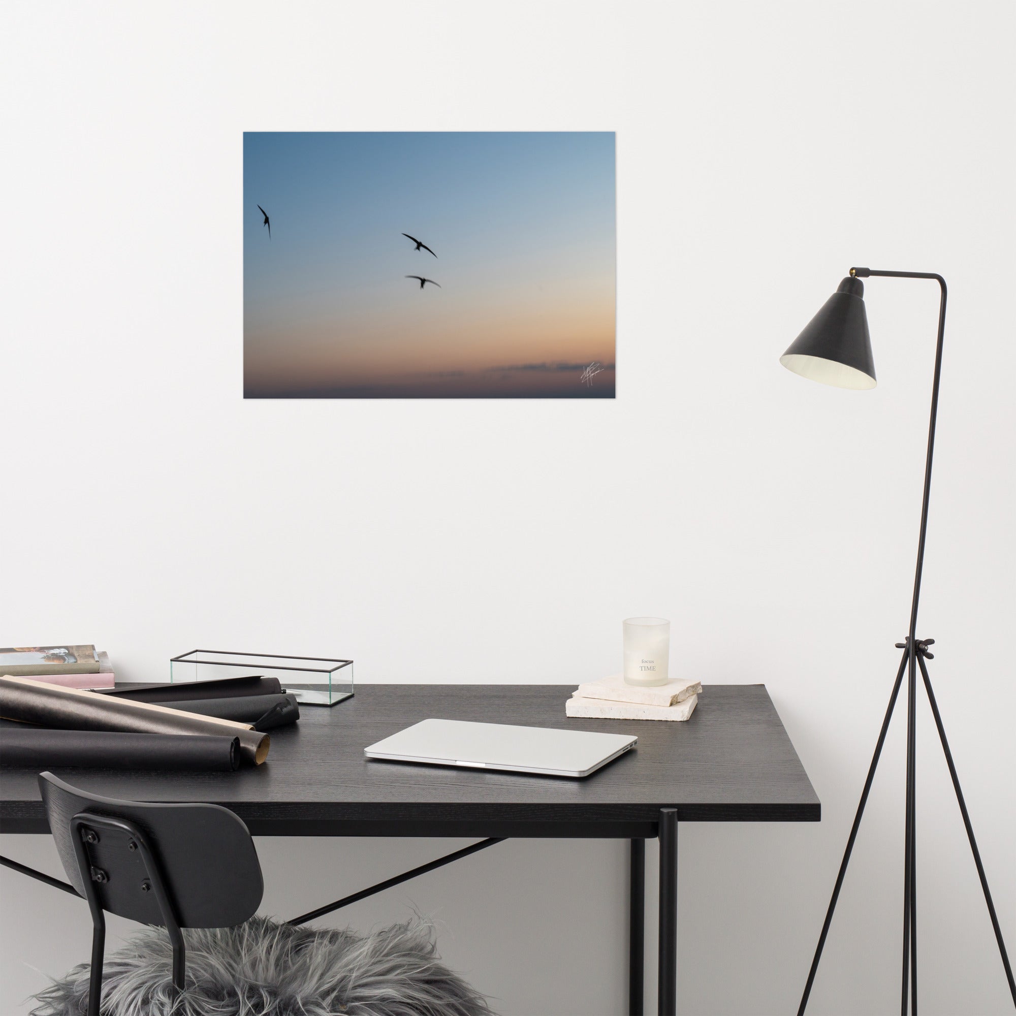 Trois oiseaux volant dans un ciel aux teintes de bleu, orange et jaune.