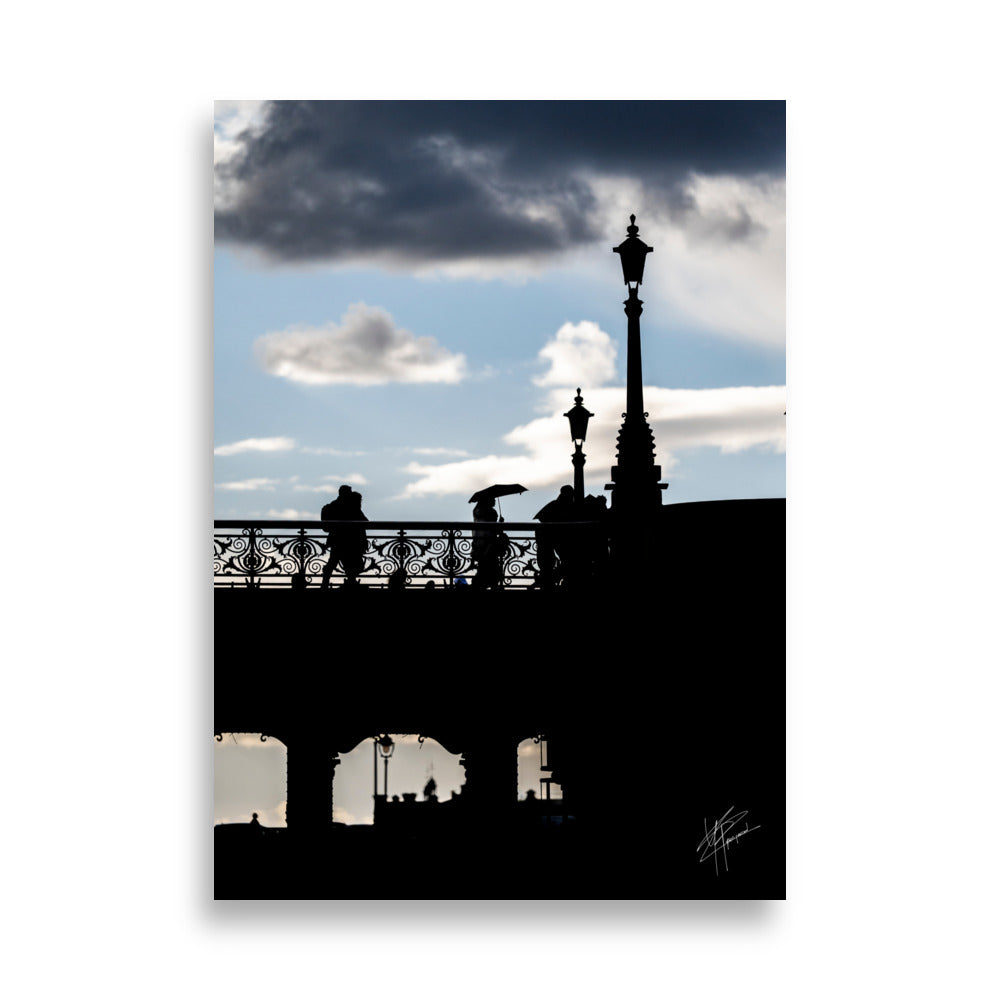 Des passants sur un pont parisien avec un ciel azur en arrière-plan, orné de nuages blancs et gris.