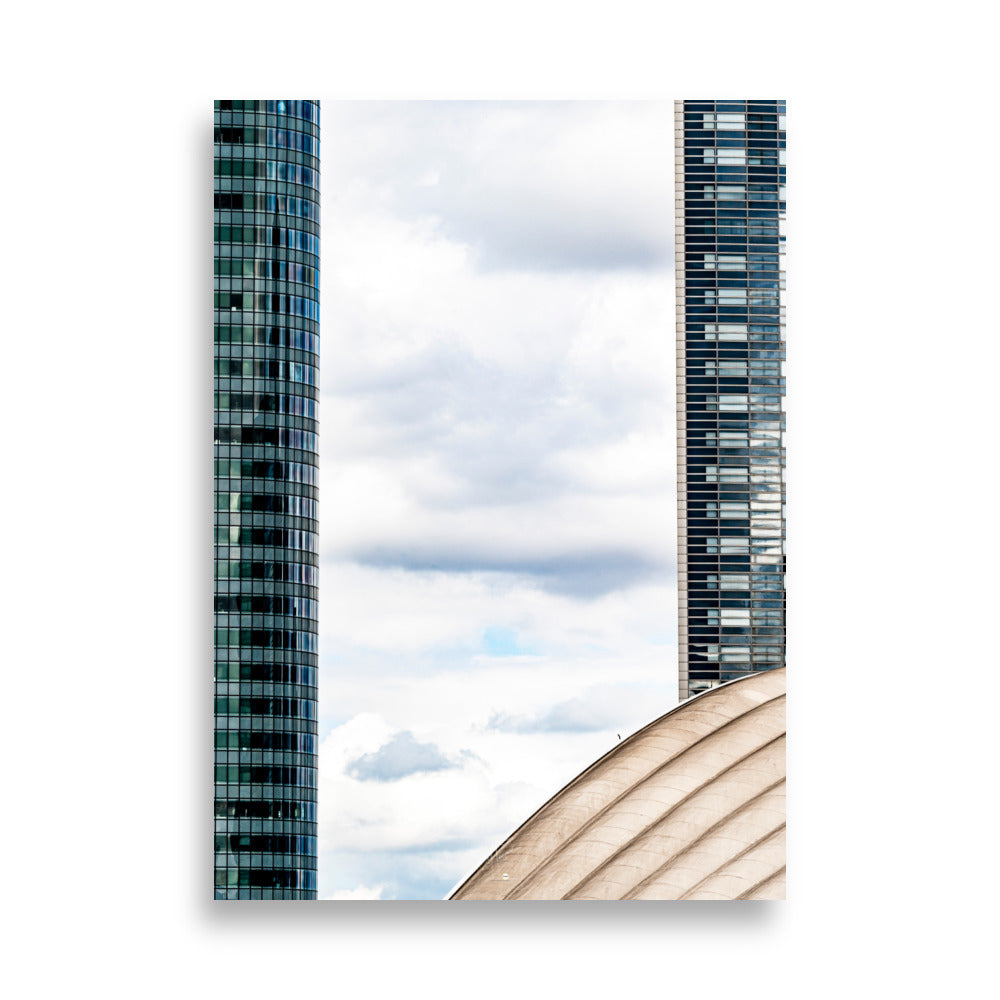 Fenêtre entre deux bâtiments en verre offrant une vue sur un ciel nuageux.