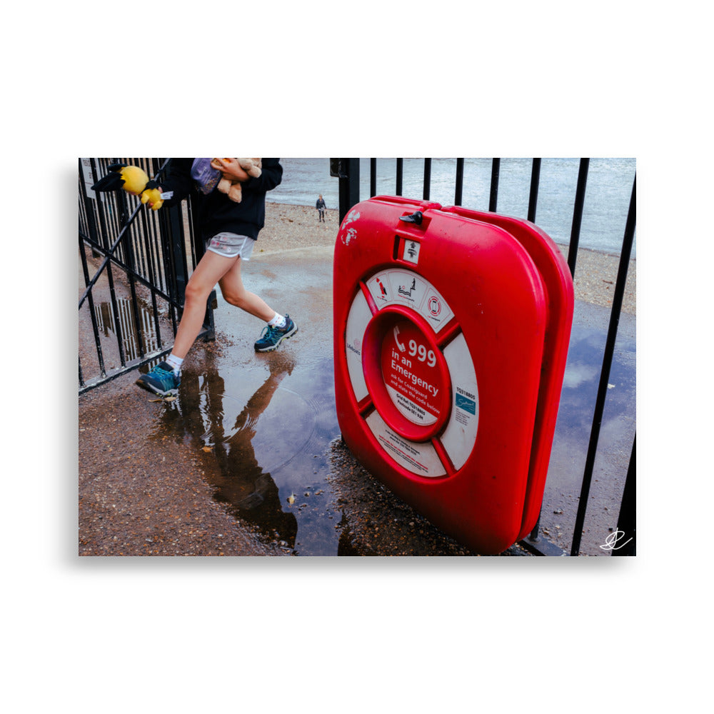 Photographie 'Il faut rentrer' par Ilan Shoham mettant en lumière une boite rouge d'urgence affichant le numéro 999, fixée sur une grille métallique, dans le contexte vibrant des rues de Londres.